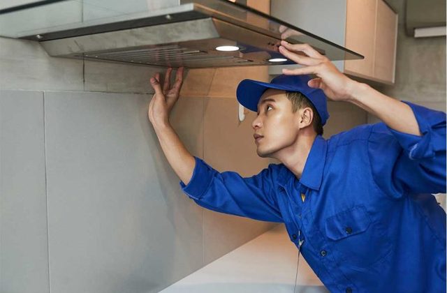 Technician installing a kitchen chimney in a Chandigarh home